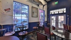 Un restaurante con vista al océano, con mesas y sillas, un cartel de advertencia sobre tiburones y un letrero de salida.