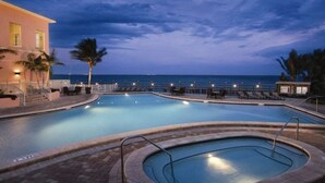 Una piscina con vista al océano al atardecer.