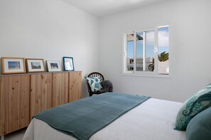 Une chambre à coucher comprenant un lit, une armoire en bois, une chaise, une fenêtre donnant sur un beau paysage et des tableaux encadrés accrochés au mur.