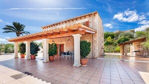 Un espacio al aire libre cubierto con una pérgola, plantas en macetas y una mesa de patio.