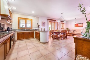 A spacious kitchen with a central island, wooden cabinets, and a dining area with a table and chairs.