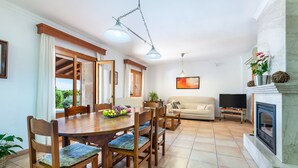 Un comedor con mesa y sillas de madera, un sofá, una chimenea y un televisor en una sala de estar.
