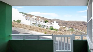 Udsigt fra en balkon med en hvid dør, over en bakke med hvide bygninger og en klar himmel.