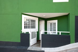 Un edificio verde con una puerta, una ventana y una barandilla, todos blancos.