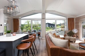 Eine geräumige Küche mit einer großen Kochinsel, ein Essbereich mit Ledersesseln und eine gemütliche Sitzecke mit einer Couch und Kissen.