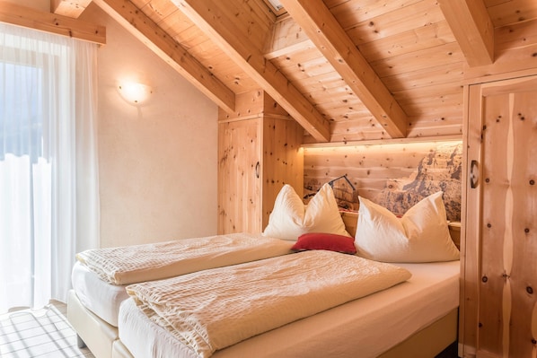 A wooden cabin room with a bed, pillows, and a wall-mounted light.