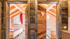 Ein Schlafzimmer im Loft-Stil mit freiliegenden Holzbalken, geneigter Decke und zwei Betten.