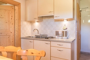 Une cuisine avec des meubles de rangement en bois, un évier, une bouilloire et un grille-pain.