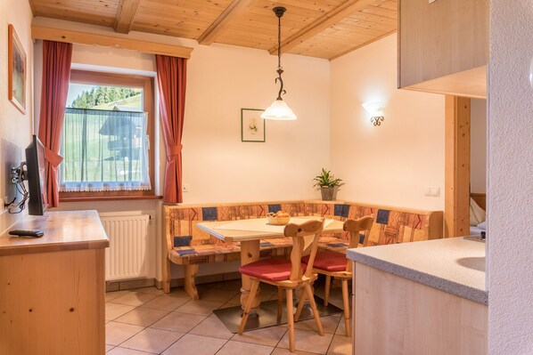 Una cocina acogedora con muebles de madera, una mesa de comedor y una ventana con cortinas.