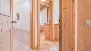Ein Flur mit Holztäfelung, gefliesem Boden und Holztüren, mit einem sichtbaren Badezimmer und Dusche.