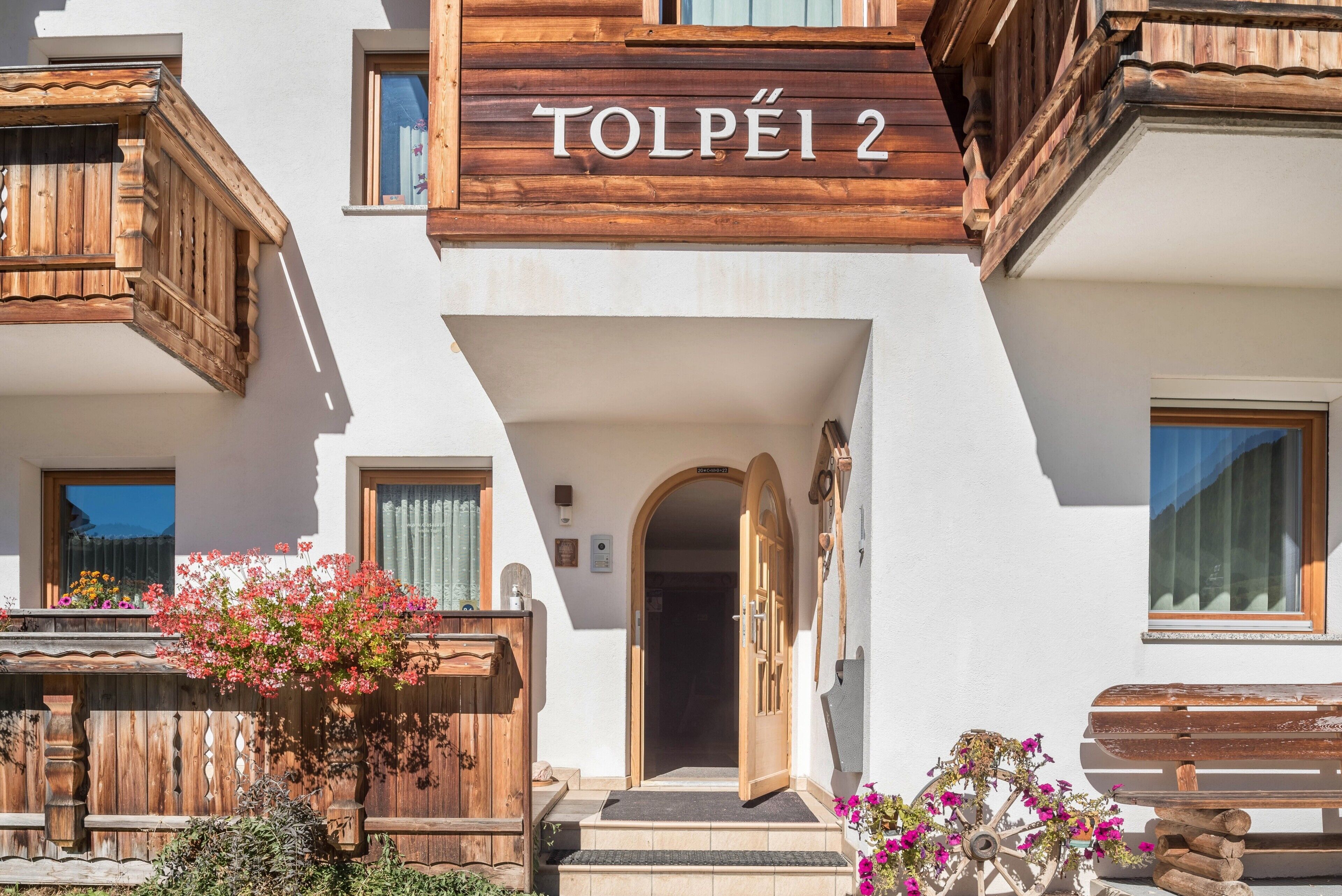 Ein Gebäude mit einem Schild, auf dem 'TOLPÉI 2' steht, und einem hölzernen Balkon.