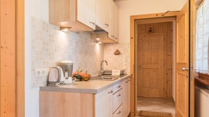 A kitchen with wooden cabinets, a countertop, a sink, and a door leading to another room. - Apartment Ciasa Raut App Santa Berbura with Mountain View, Balcony & Wi-Fi (La Val)