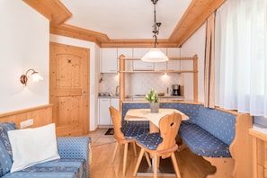 A compact kitchen with wooden cabinetry, a dining table, and a bench.