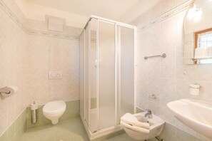 A bathroom with a toilet, a shower enclosure, a sink, and a mirror.