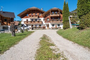 A hotel with a gravel driveway leading to a building with balconies and wooden architecture.