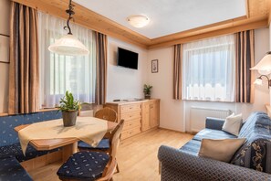 Et hyggeligt værelse med spisebord, stole, sofa og fjernsyn.