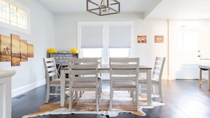 Un coin repas avec une table et des chaises en bois, un tapis en peau de vache et des œuvres d’art accrochées aux murs.