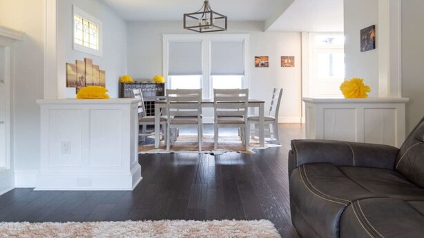 Un salon moderne avec un parquet en bois foncé, un canapé en cuir et un tapis moelleux.