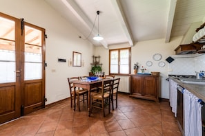 Una cocina con armarios de madera, una mesa de comedor con sillas, una lámpara colgante y un ventanal con vistas.