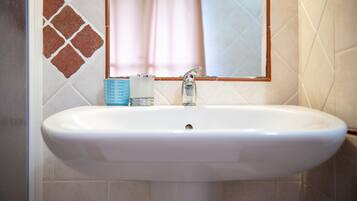 A bathroom with a white sink, a mirror, and a tiled wall.