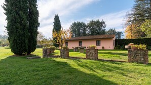 Un bâtiment à la façade rose, doté de piliers en pierre et d’une pelouse bien entretenue.