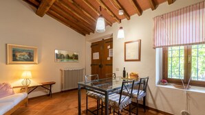 Un coin repas avec une table en verre, des chaises, une lampe et des œuvres d’art accrochées aux murs.