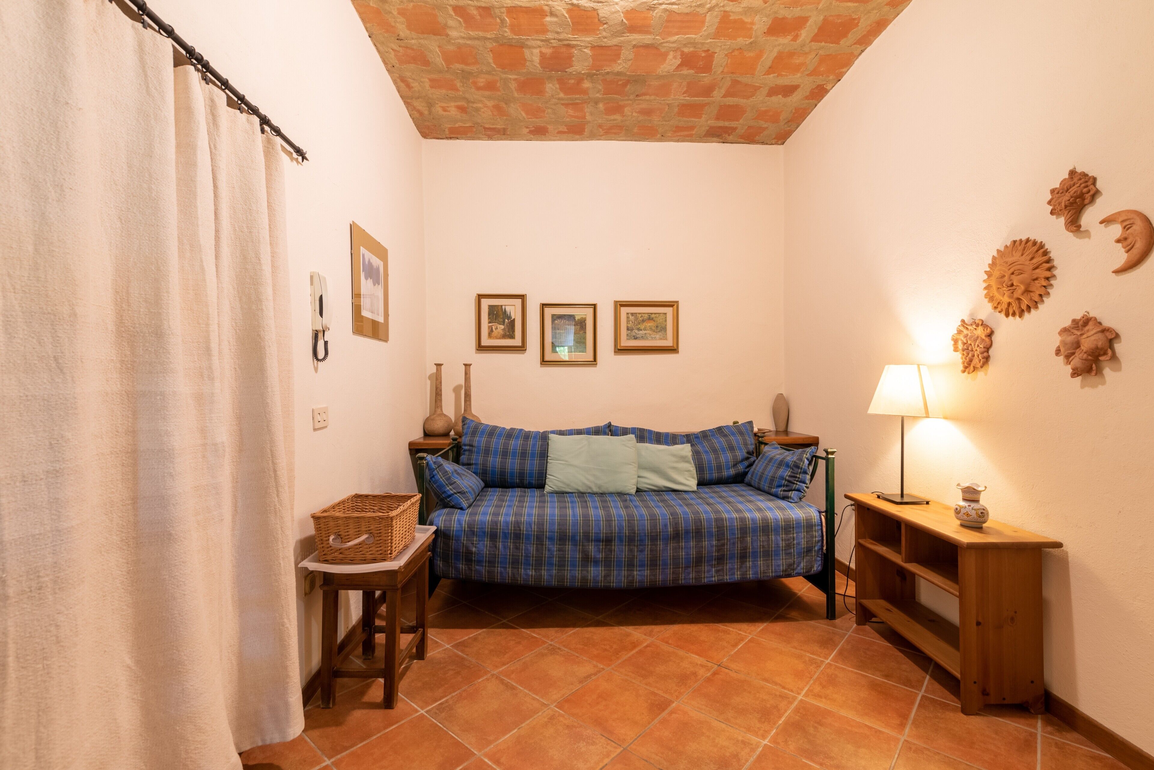 Une pièce chaleureuse avec un canapé à carreaux bleus, une petite table, une lampe et un mur orné de motifs décoratifs représentant le soleil et la lune.