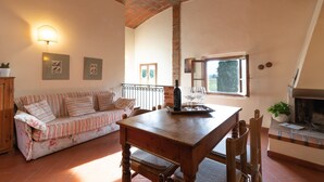 A cozy living room with a wooden table, sofa, and fireplace. - Villa 'Il Fienile Il Sole Verde' with Shared Pool and Wi-Fi (Bucine)