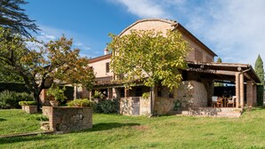 A stone house with a covered porch, a brick wall, and a grassy yard. - Villa 'Il Fienile Il Sole Verde' with Shared Pool and Wi-Fi (Bucine)