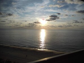 Un atardecer sobre un mar tranquilo con una playa al frente.
