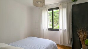 Una camera da letto con un letto, una finestra con tende, una lampada a sospensione e una pianta.