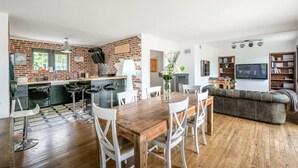 Una cucina moderna con parete in mattoni, tavolo da pranzo in legno e sgabelli da bar.