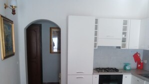A narrow hallway leading to a kitchen with white cabinets, a stove, and a red kettle. - Pet-Friendly Apartment 'Casa Rosciano' with Mountain View & Garden (rosciano)