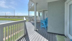 A covered porch with a view of a grassy area and a body of water.