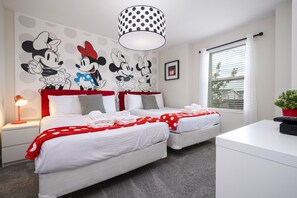 A hotel room with two beds, a desk, a lamp, a Mickey Mouse wall decal, and a window with blinds. - Last Minute Disney! Private Pool, Hot Tub, Game Room & Themed Bedrooms. Book Now! #29466 (Orlando)
