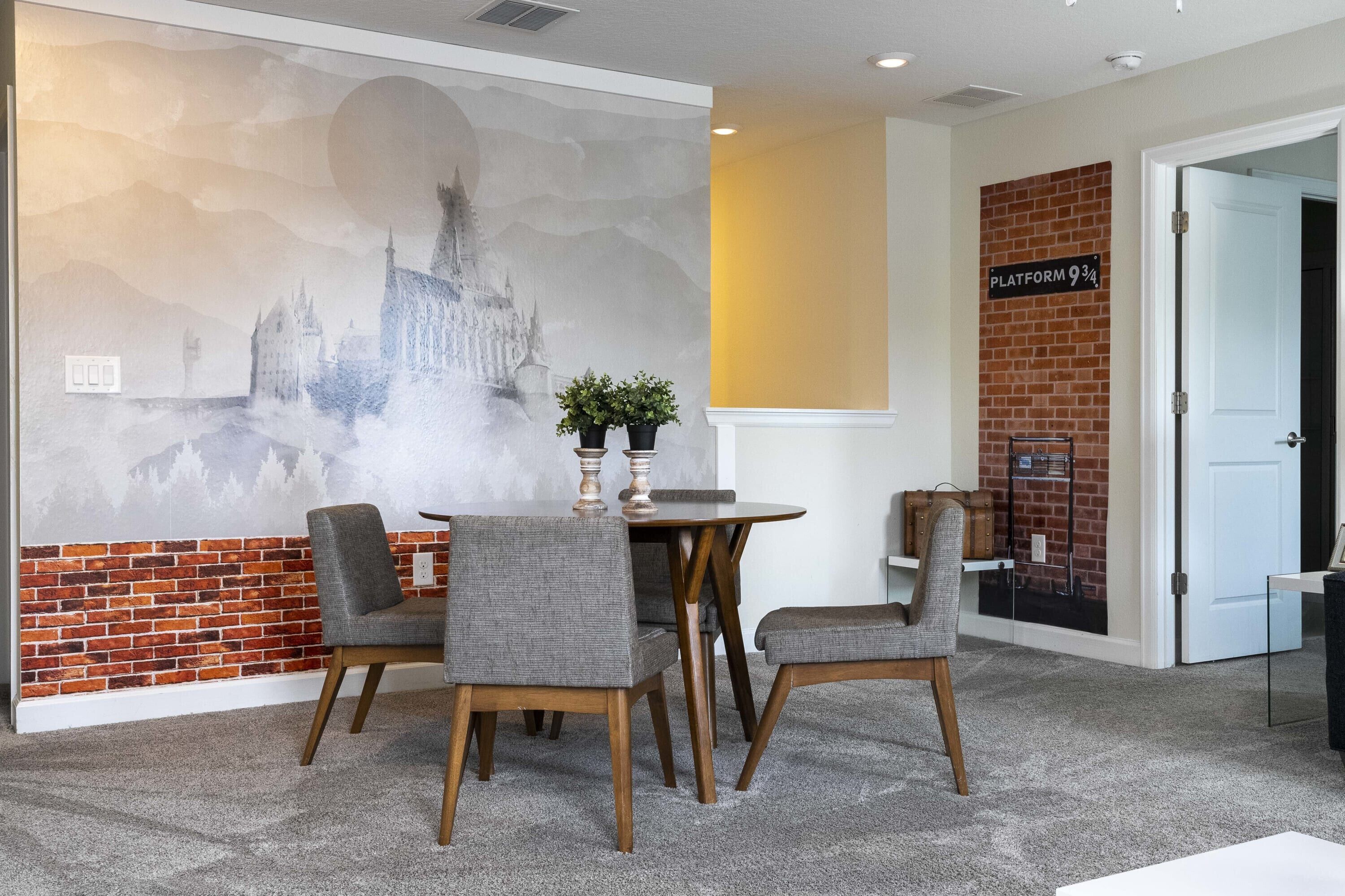 A conference room with a mural of a castle, a round table with chairs, and a brick accent wall.
