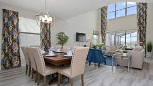 Un coin repas avec une table ronde, des chaises et un lustre. Le salon comprend un canapé et une table basse.