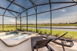 Relax in a serene hot tub area with a tranquil view of the water and lush surroundings, accompanied by two comfortable lounge chairs.