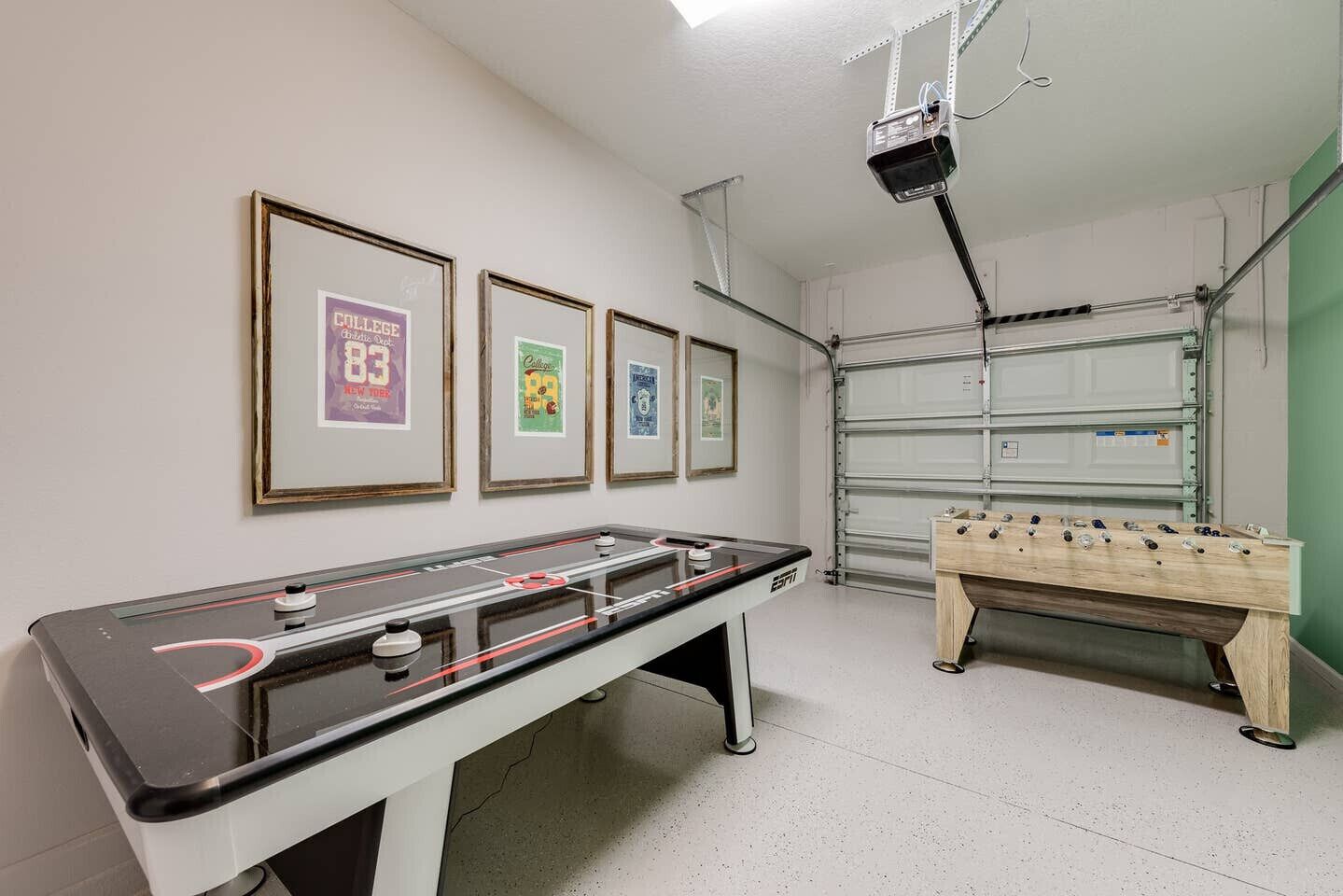 Une pièce avec un baby-foot, une table de billard et des affiches encadrées accrochées au mur.