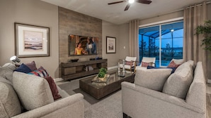 A modern living room with a flat-screen TV, comfortable seating, a coffee table, and a large window with a view.