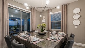 A dining area with a glass table, chairs, and a chandelier.