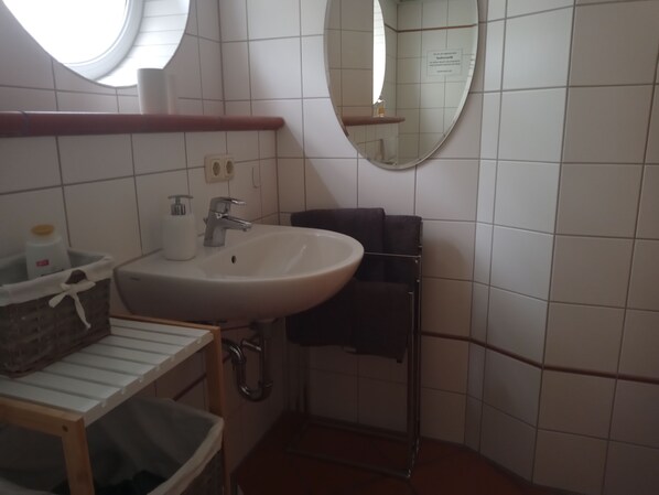 Un baño con lavabo blanco, espejo y paredes con azulejos.