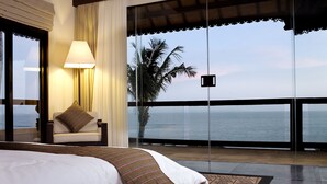 Een slaapkamer met een bed, een stoel, een lamp en uitzicht op de oceaan.