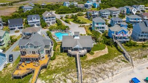 Vista aérea de una zona residencial costera con casas, piscina y playa.