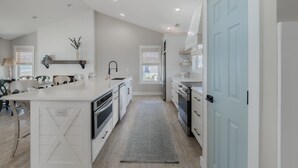 Una cocina moderna con armarios blancos, una isla central y una puerta azul.