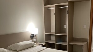 Ein Hotelzimmer mit Bett, Nachttisch mit Lampe und integrierten Regalen.