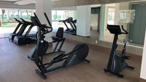 Ein Fitnessstudio mit mehreren Trainingsgeräten, darunter Laufbänder und Fahrrädern, in einem großzügigen Raum mit großen Fenstern.