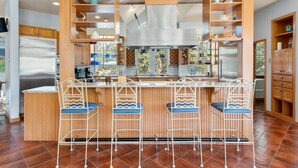 Una cucina con mobili in legno, un frigorifero in acciaio inossidabile e un'area bar con tre sgabelli.