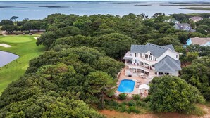 Un'ampia casa con piscina e un campo da golf sullo sfondo.