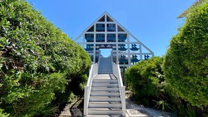 A staircase leading to a building with a triangular roof and multiple windows.